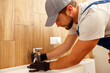 © Kostiantyn - Serious plumber, male worker in uniform installing tap or bathroom faucet