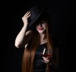 girl, in a hat, with a glass of cognac on a black background