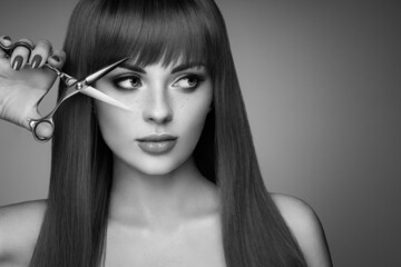 Wall Mural - beautiful young woman with a bright makeup and a smooth long hair holds metal scissors. hair salon, 