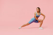 © ViDi Studio - Full size young sporty athletic fitness trainer woman wear blue tracksuit spend time in home gym train do stretch legs squat exercise isolated on pastel plain pink background. Workout sport concept.