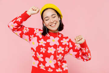 Wall Mural - Smiling happy woman of Asian ethnicity 20s wear red knitted sweater beret headphones listen to music dance isolated on plain pastel pink background studio portrait. People lifestyle fashion concept.