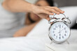 © Prostock-studio - Time To Wake Up. Man Reaching Alarm Clock On Bedside Table, Closeup