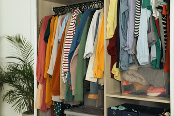 Wall Mural - Wardrobe closet with different stylish clothes and home stuff in room. Fast fashion