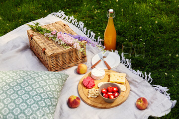 Wall Mural - leisure and drinks concept - close up of food, drinks and basket on picnic blanket on grass