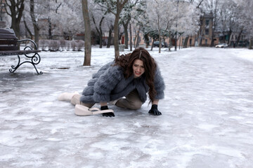 Young woman fallen on slippery icy pavement in park