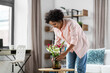 © Syda Productions - household, home improvement and interior concept - happy smiling young woman placing flowers on coffee table