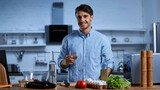 Fototapeta  - happy young man holding glass of white wine near table with fresh ingredients.