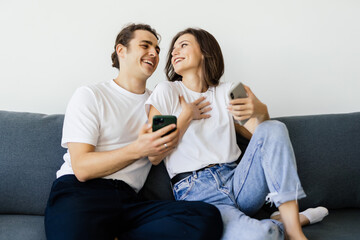 Mobile addiction concept, young couple using smartphones relaxing on sofa