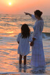 © aletia2011 - Mother with daughter in white clothing on sandy beach, back view