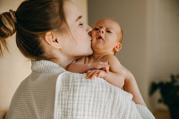 Wall Mural - Mother kissing newborn baby on cheek.