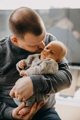 Wall Mural - Closeup of father holding newborn baby in arms, kissing him on cheek.