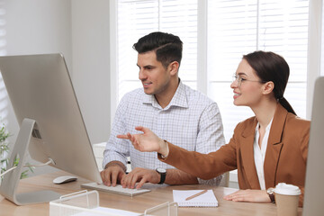 Wall Mural - Businesswoman helping intern with work in office