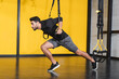 © LIGHTFIELD STUDIOS - Side view of muslim sportsman working out with suspension straps in gym.