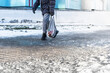 People walk on a slippery road made of melted ice. View of the legs of a man walking on an icy pavement. Winter road in the city. Injury after a fall on an icy road.