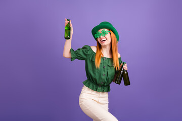 Wall Mural - Photo of funny red hair millennial lady drink beer holiday wear eyewear green bare shoulders blouse cap isolated on violet background