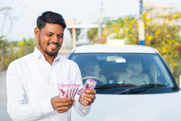 Happy smiling cab driver counting money in front of car - concept of profit business, loan approval, financial, banking and self employment.