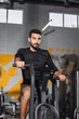 © LIGHTFIELD STUDIOS - Muslim sportsman training on elliptical trainer in blurred gym.