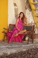 Women In A Pink Dress Sits On A Bench In Milos Greece