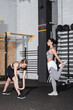 © LIGHTFIELD STUDIOS - Interracial sportswomen stretching near equipment in gym.
