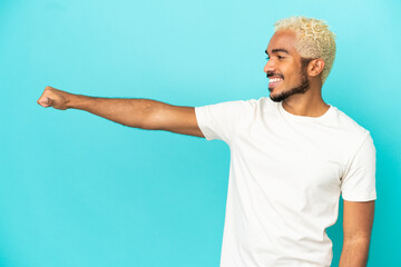 Poster - Young Colombian handsome man isolated on blue background giving a thumbs up gesture