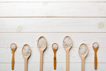 Salt On Many Wooden Spoon On Wood Background. Spoons With Different Salt