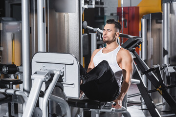 Wall Mural - Sportsman in sportswear training on leg press machine near sports equipment in gym.