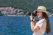 © skumer - Young travel lady in dress takes photo with professional camera at sunny day. Young female photographer at her vacation trip in europe