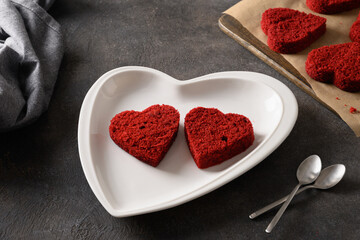 Making heart shaped red velvet cake for two for Valentine's day on dark background. Tasty homemade dessert. Close up.