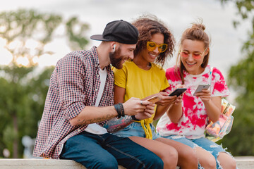 Wall Mural - happy young company of smiling friends sitting in park