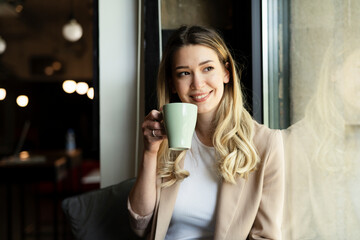 Wall Mural - Young businesswoman drinking coffee in her office.