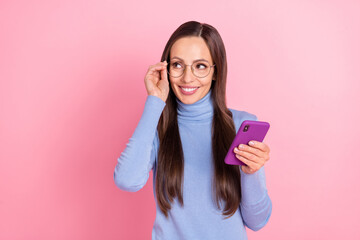 Poster - Photo of minded thoughtful lady hold telephone look empty space wear specs blue turtleneck isolated pink color background