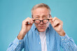 Mature man squinting wearing eyeglasses, looking at camera