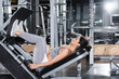 © LIGHTFIELD STUDIOS - Side view of middle east sportswoman exercising on leg press machine in gym.