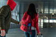 © NFstock - Back view of the woman with trolley bag walking through the airport while unrecognizable robber stealing her things. Stock photo