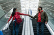 © NFstock - Low angle view of the happy married couple holding hands of each other while standing at the moving staircase and riding at the different ways. People at the airport concept