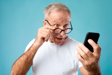 Excited mature man using mobile phone, looking at screen