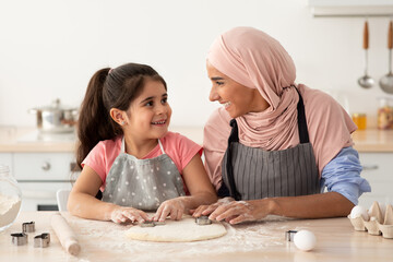 Wall Mural - Smiling Muslim Mom With Her Little Daughter Baking Together In Kitchen