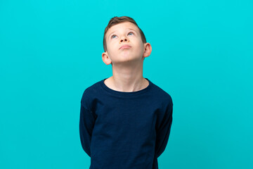 Wall Mural - Little kid boy isolated on blue background and looking up