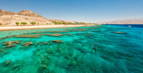 Wall Mural - Beautiful coral reefs of the Red Sea, sandy beaches, small tourist hotels and Sinai mountains near Eilat – famous tourist resort and recreational city in Israel.