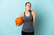 © luismolinero - Young woman playing basketball isolated on blue background with fingers crossing and wishing the best