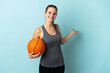 © luismolinero - Young woman playing basketball isolated on blue background extending hands to the side for inviting to come