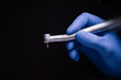 a dental tip and a metal bur in dentistry treats caries a blue gloved hand holds