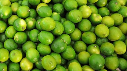 Wall Mural - Close up of Persian limes on display on a market stall.  Slow motion.