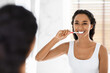 © Prostock-studio - Happy Young Middle Eastern Woman Brushing Her Teeth With Toothbrush In Bathroom