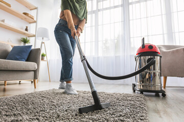 Wall Mural - Closeup of muslim woman cleaning rug carpet with vacuum cleaner