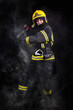 © blanke1973 - Firefighter fully equipped with helmet and ax in smoke, black background