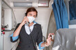 © Kostiantyn - Female stewardess in medical mask talking on telephone in airplane