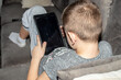 The boy plays in the tablet at home on the couch. Children's addiction to computer games and gadgets.
