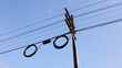Black boxes and cable reels on poles. Internet box or splitter box with high-speed fiber optic cable hanging on a metal electric pole on a blue background with copy space. Selective focus