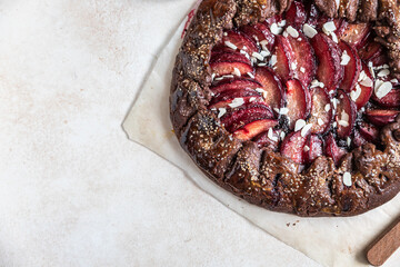 Wall Mural - Homemade galette or open pie with chocolate, plum and almond on light background. Top view.